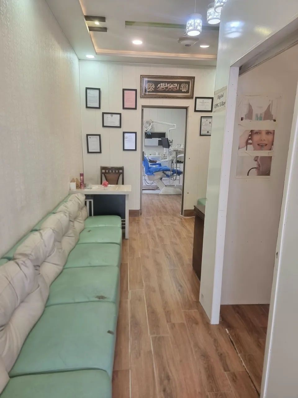 Waiting area at Al-Rehman Dental Care with sofa seating, framed certificates on the wall and a view into the dental treatment room